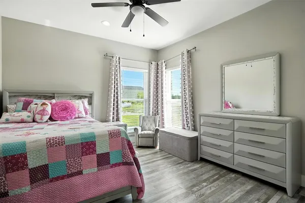 a bedroom with a bed a dresser and wooden floor