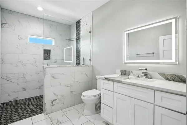 a bathroom with a granite countertop sink toilet a mirror a vanity and a shower
