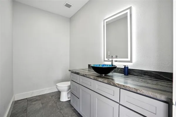 a bathroom with a granite countertop toilet and sink