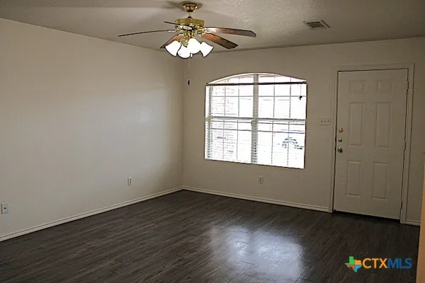 an empty room with wooden floor and windows