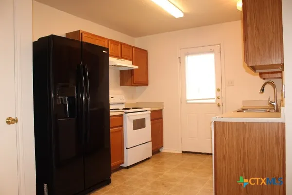 a kitchen with granite countertop a refrigerator and a sink