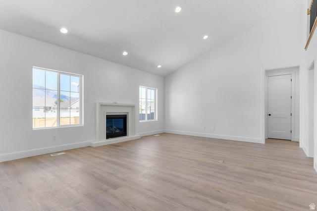 11711 South Halls Crk Road Draper, UT 84020 - Photo 12 of 31 Unfurnished living room with vaulted ceiling, a glass covered fireplace, recessed lighting, and light wood-style flooring