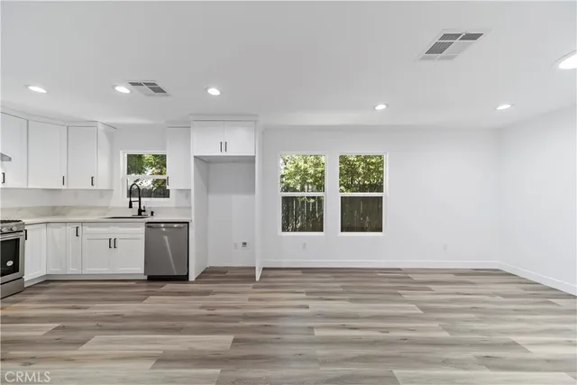 a large white kitchen with wooden floors and white walls