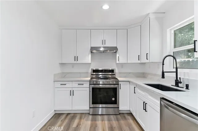 a kitchen with granite countertop white cabinets and stainless steel appliances