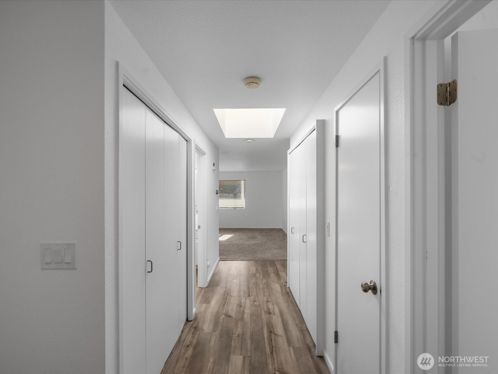 8225 212th Street Southwest, Unit 302 Edmonds, WA 98026 - Photo 5 of 16 a view of a hallway with wooden floor and a bathroom