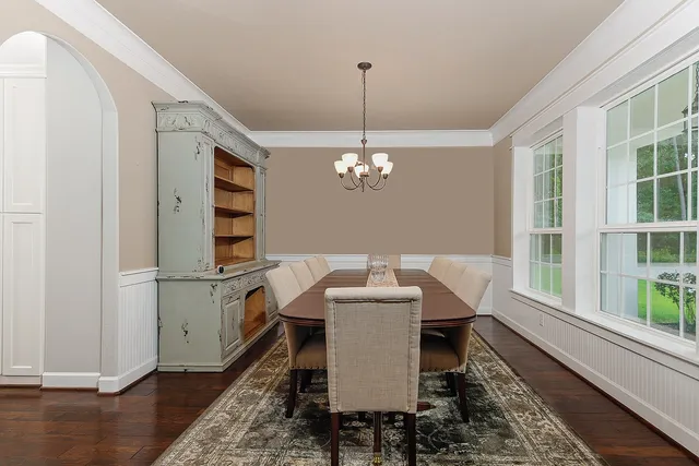 a dining room with wooden floor a chandelier a glass table and chairs