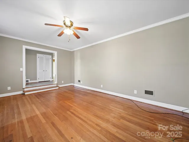 an empty room with wooden floor ceiling fan and windows