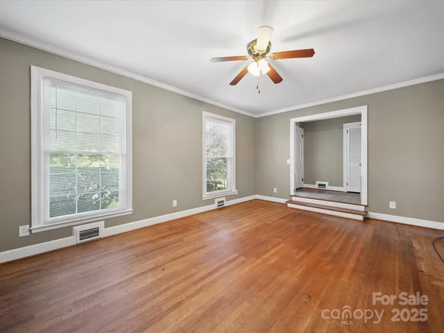 a view of an empty room with wooden floor and a window