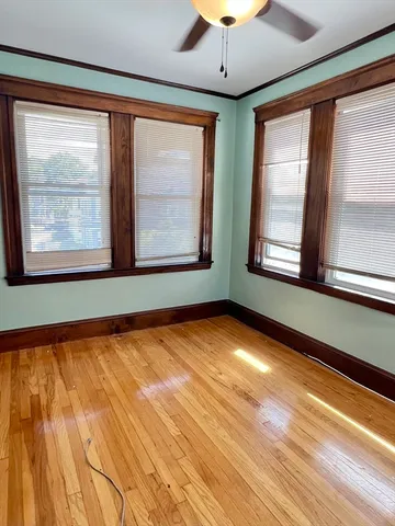 a view of an empty room with a window and wooden floor
