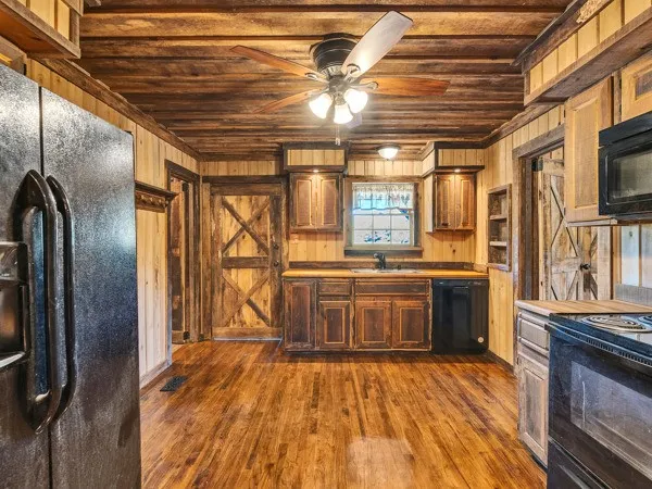 a large kitchen with stainless steel appliances wooden floors and large window