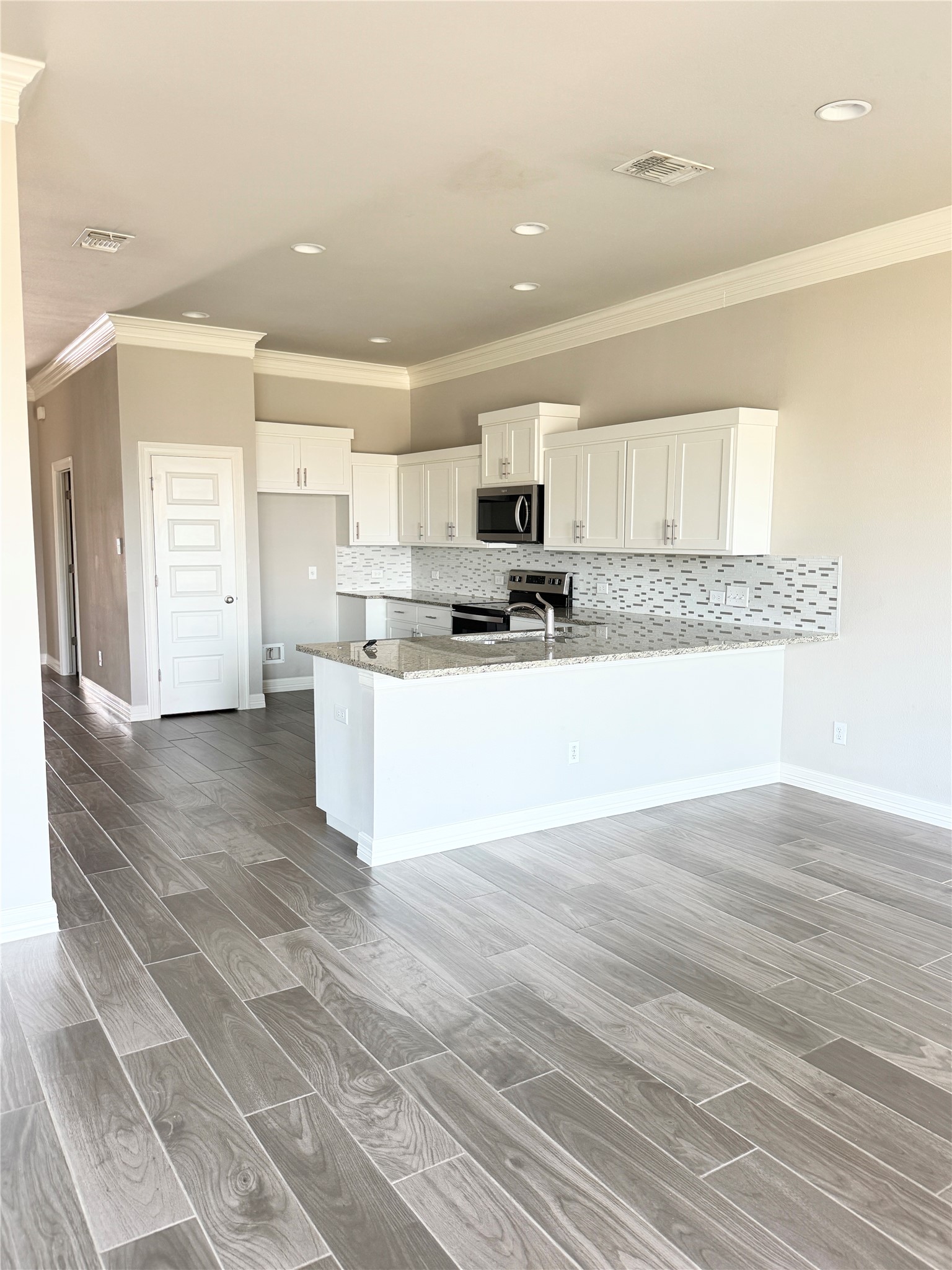 105 Everett Court, Unit B Jarrell, TX 76537 - Photo 2 of 16 a large white kitchen with kitchen island a sink a stove a refrigerator and white cabinets