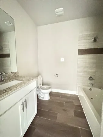 a bathroom with a granite countertop sink a toilet and bathtub