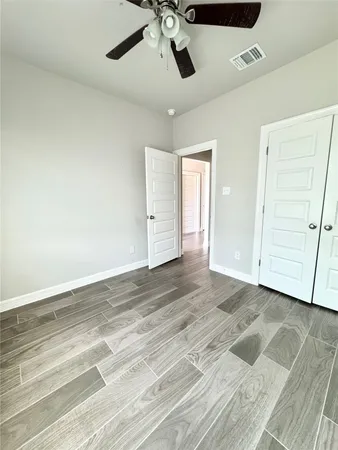an empty room with a ceiling fan and wooden floor