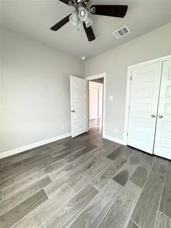 an empty room with wooden floor and ceiling fan
