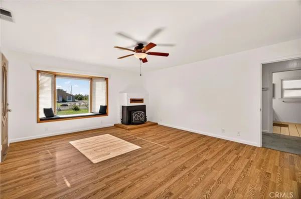 a view of an empty room with window and wooden floor