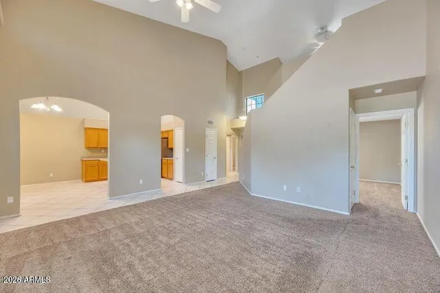 a view of an empty room with kitchen and a window