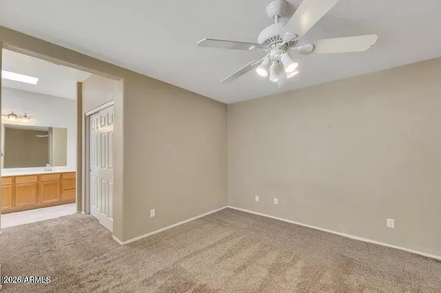 an empty room with chandelier fan and windows