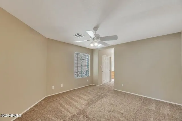 an empty room with chandelier fan and windows