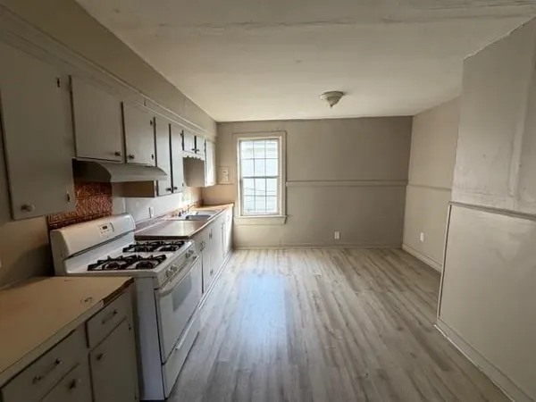a kitchen with granite countertop a stove a sink dishwasher and a refrigerator with wooden floor