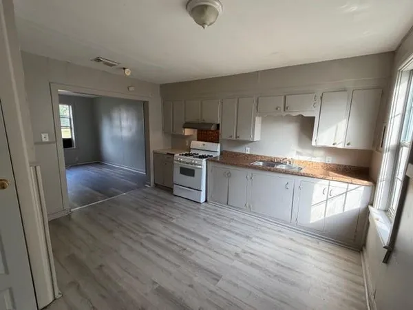a kitchen with granite countertop a stove a sink and a refrigerator