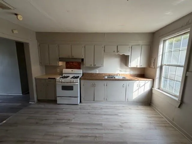 a kitchen with granite countertop a refrigerator stove and sink