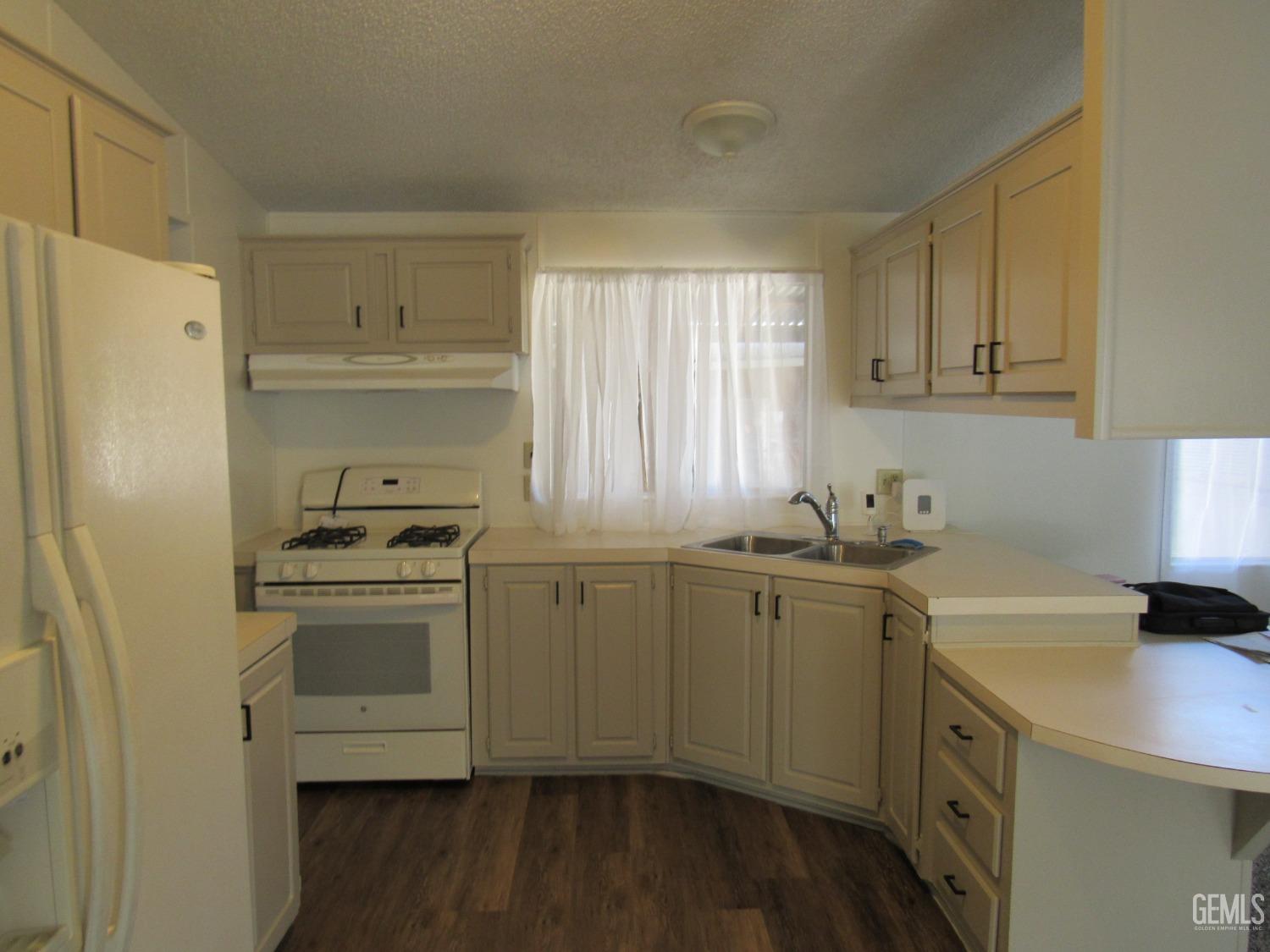 Undisclosed Address Bakersfield, CA 93304 - Photo 4 of 26 a kitchen with a sink a stove a refrigerator and cabinets