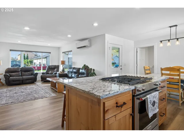 a kitchen with stainless steel appliances granite countertop a stove top oven a dining table and chairs with wooden floor