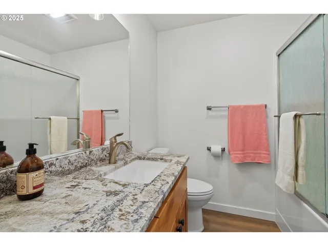 a bathroom with a granite countertop sink a toilet and a mirror
