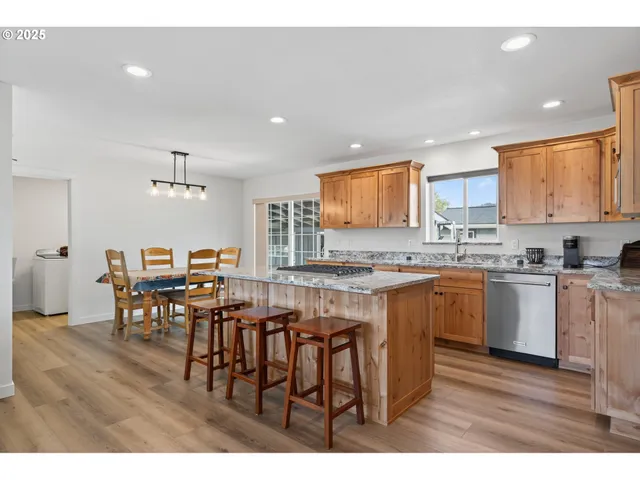 a kitchen with stainless steel appliances granite countertop wooden floors a table and chairs
