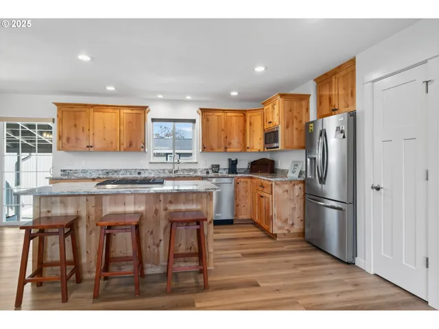 a kitchen with stainless steel appliances granite countertop a refrigerator a stove a sink and a microwave