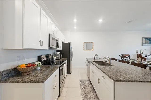 a kitchen with granite countertop stainless steel appliances a sink a counter top space cabinets and stove top oven