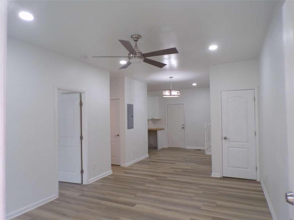 an empty room with wooden floor and a ceiling fan