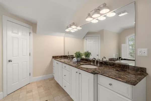 a bathroom with a granite countertop double vanity sink and a mirror