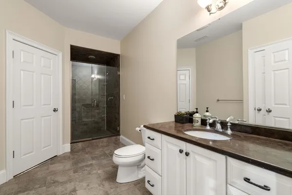 a bathroom with a granite countertop sink toilet and shower