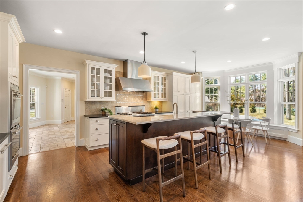 21 Westerly Road Weston, MA 02493 - Photo 7 of 38 a kitchen with stainless steel appliances granite countertop a stove top oven a sink a dining table and chairs with wooden floor