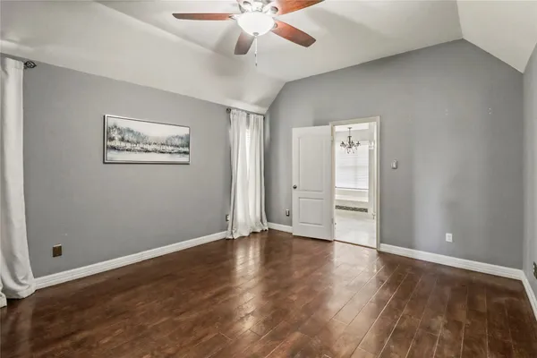 an empty room with wooden floor and ceiling fan