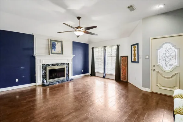 a view of a livingroom with a fireplace a ceiling fan and windows