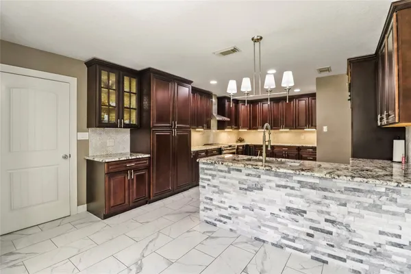 a kitchen with granite countertop a refrigerator and a stove top oven