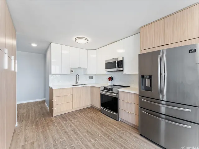 a kitchen with a refrigerator stainless steel appliances wooden floor and cabinets