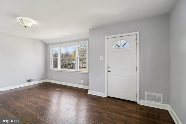a view of an empty room with wooden floor and fireplace