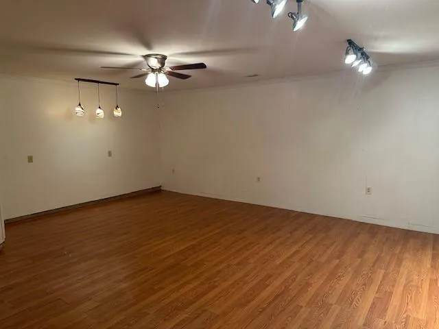 an empty room with wooden floor fan and windows