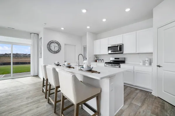 a kitchen with a table chairs a stove a microwave and cabinets