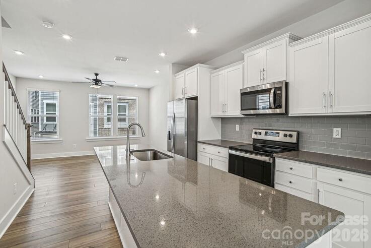 4375 Raleigh Street, Unit C1 Charlotte, NC 28213 - Photo 6 of 19 a kitchen with stainless steel appliances granite countertop a refrigerator a stove top oven a sink dishwasher and wooden cabinets with wooden floor