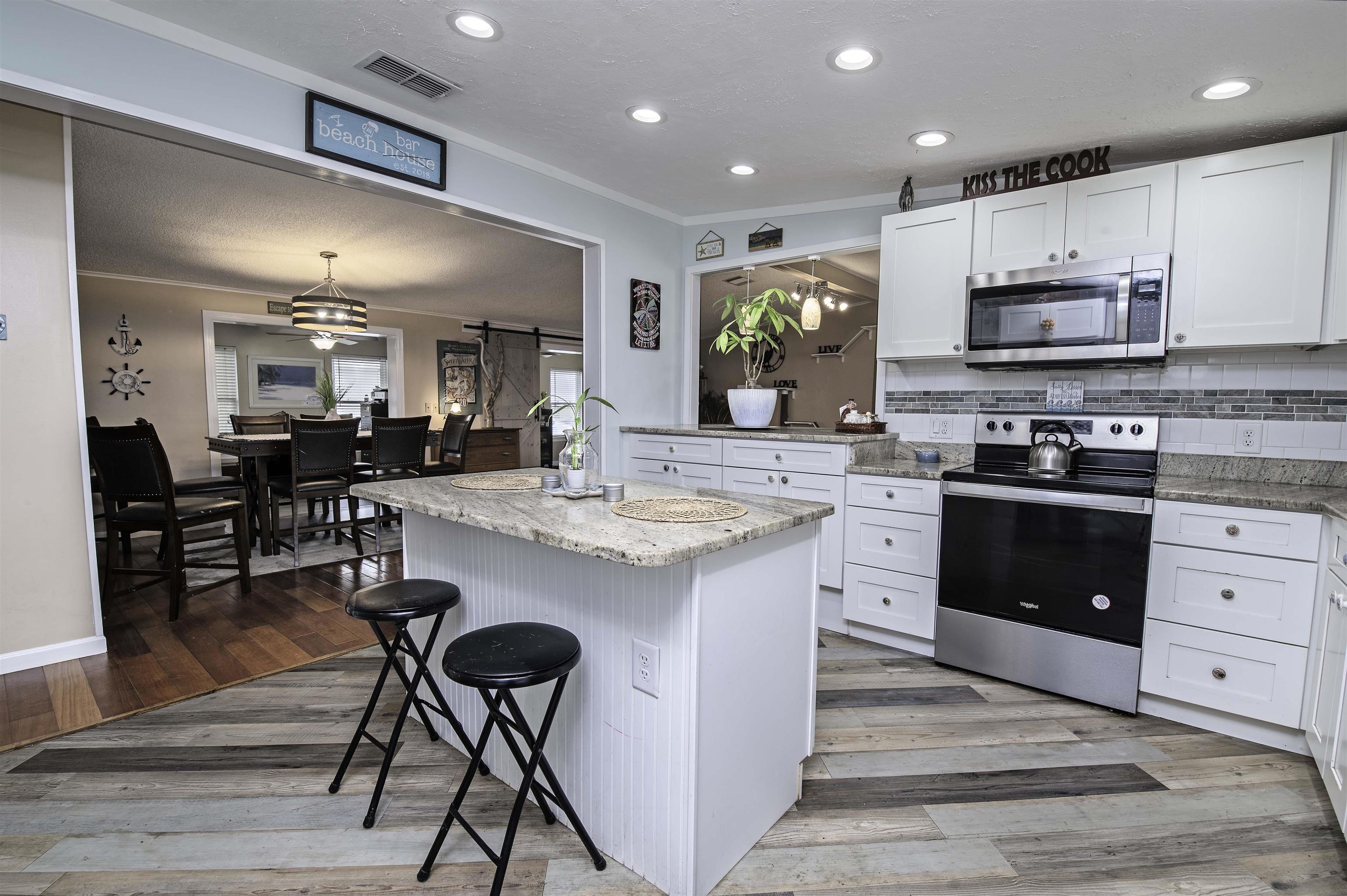 266 Pizarro Road St. Augustine, FL 32080 - Photo 10 of 26 a kitchen with stainless steel appliances kitchen island granite countertop a stove top oven a sink a dining table and chairs with wooden floor