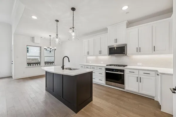 a kitchen with stainless steel appliances granite countertop a sink stove and white cabinets with wooden floor