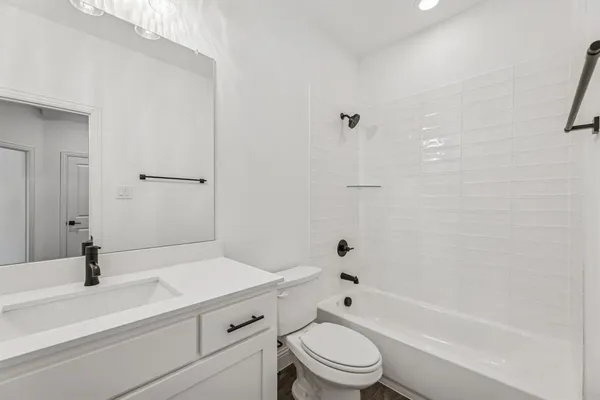 a bathroom with a bathtub shower sink mirror vanity and toilet