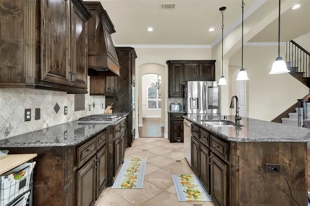a kitchen with stainless steel appliances granite countertop a sink a stove and a wooden floors