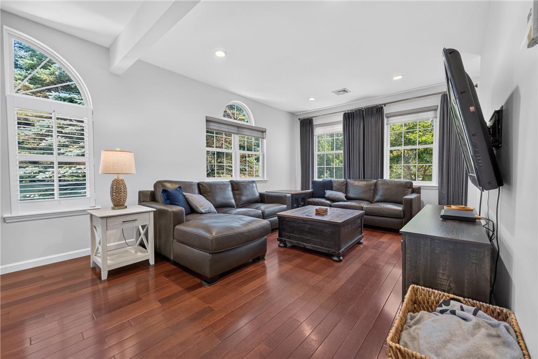 220 Pennbrook Road Stroudsburg, PA 18360 - Photo 18 of 60 Natural light streams into this living room through arched and rectangular windows, illuminating rich hardwood flooring.