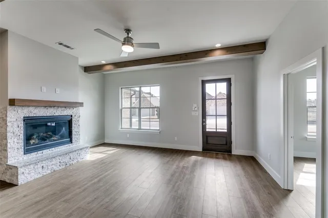 a view of an empty room with wooden floor fireplace and a window