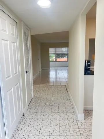 a view of a hallway with wooden floor and a living room